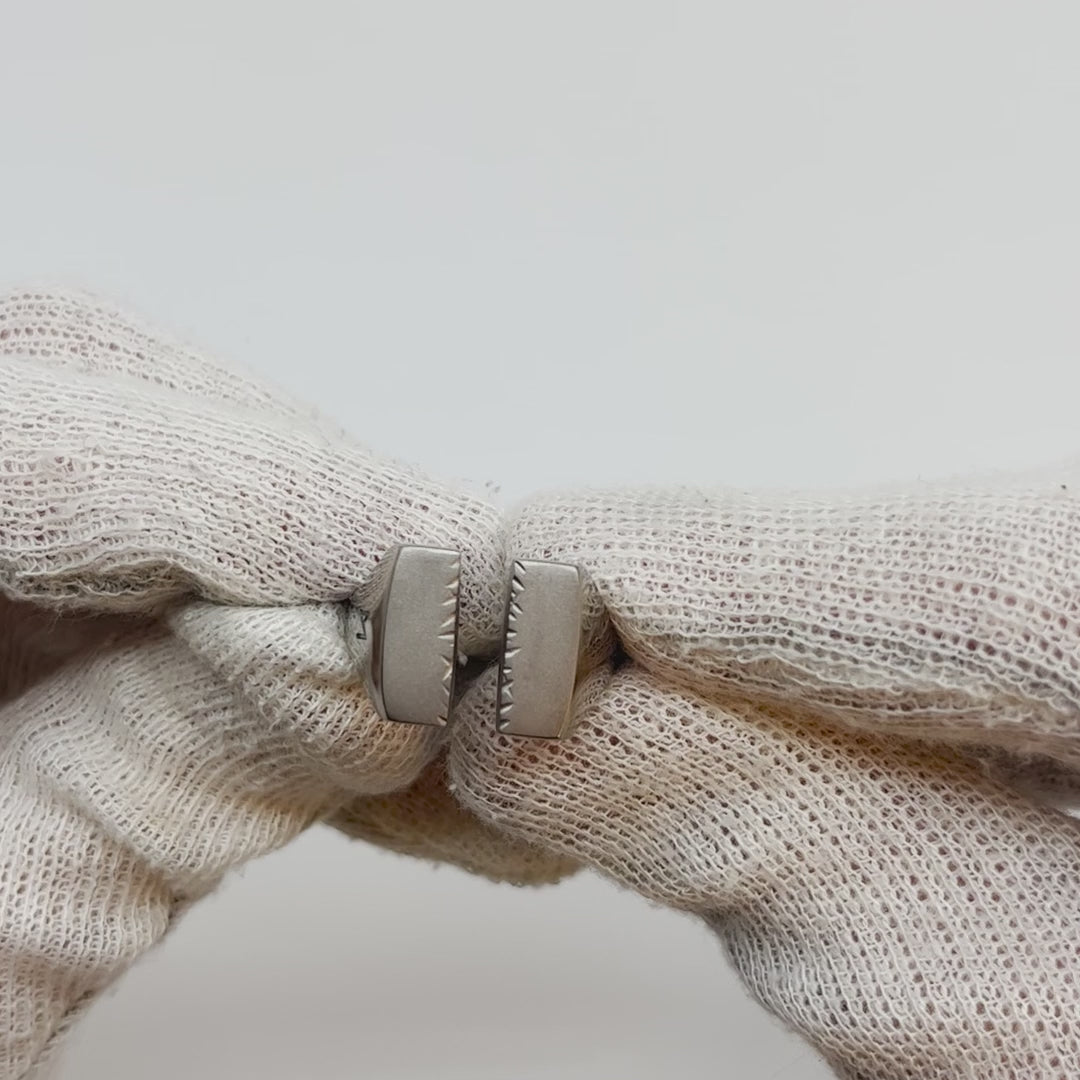 Showing single silver-colored titanium signet ring, 15x15 mm wide surface witch has been cut through the middle, from all angles.